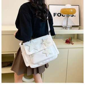 Detailed side view of white crossbody messenger bag with plush star patches on canvas