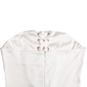 Detail of light pink satin dress back featuring lace-up ribbons and a sleek hidden zipper