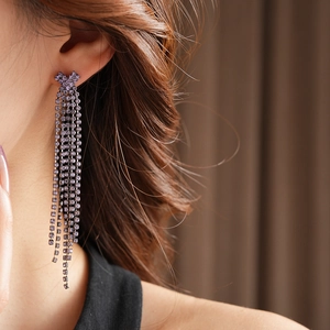 Détail d'une boucle d'oreille à pampille violette et nœud strass porté par un mannequin
