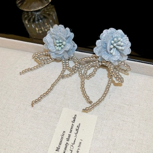 Detail of blue fabric flower earrings with silver beaded tassels and bow accents