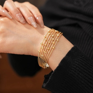 Vue détaillée d'un bracelet multicouche à perles dorées sur un poignet en gros plan