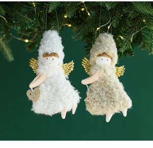 Detail of plush white Christmas angel dolls with gold wings hanging on a festive tree branch