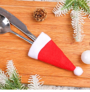 Close-up of red and white Santa hat cutlery holders with knife and spoon on wooden board