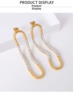 Detail of gold U-shaped earrings with fine zircon inlay on minimalist polished steel