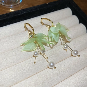 Detail of green acrylic petal earrings with gold tassels and elegant white pearls