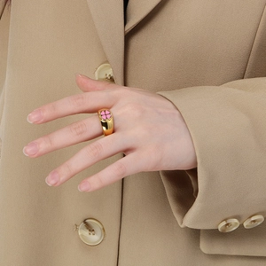 Close-up of golden four-leaf clover ring with pink enamel on female model finger