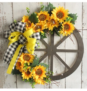 Detail of wooden wheel sunflower wreath with rustic burlap bow on white wood background