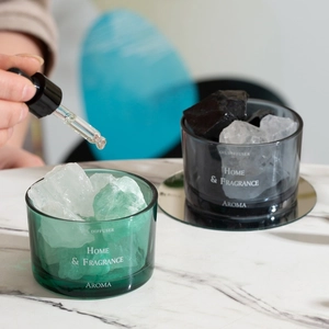 Elegant crystal stone oil diffuser set in green and black glass jars on marble surface