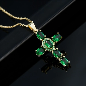 Cross necklace with green emerald gemstones on a 18K gold plated chain, 45-degree angle view