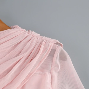 Détail du tissu en tulle rose avec plis aux épaules sur un cintre en bois clair