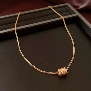 Close-up of a 24k gold plated cylinder necklace with leaf patterns and sparkling crystals