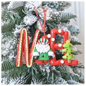 Detail of a red NOEL polymer clay Christmas ornament hanging on a snowy tree branch