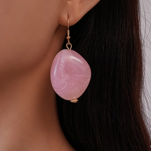 Detail of pink marble resin drop earring with gold hook worn by a model