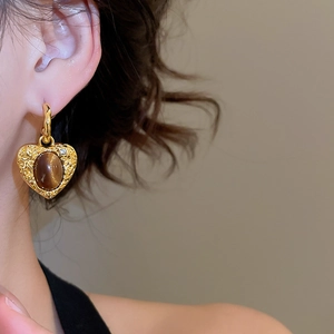 Macro detail of vintage heart earring with tiger eye stone and embossed gold textures