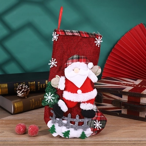 Detail of red linen Christmas stocking with 3D Santa plush and festive plaid accents