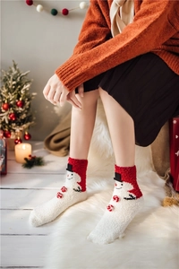 Close-up of cozy coral fleece Christmas socks with snowman design and festive red pom-poms
