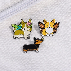 Detailansicht von drei süßen Corgi-Emaille-Pins mit Schmetterlingsflügeln auf Segeltuch