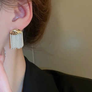 Detail of metallic fringe tassel earrings with hammered gold finish on a model