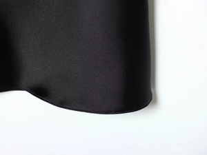 Détail de la texture satinée noire et des coutures de haute qualité sur l'ourlet de la robe