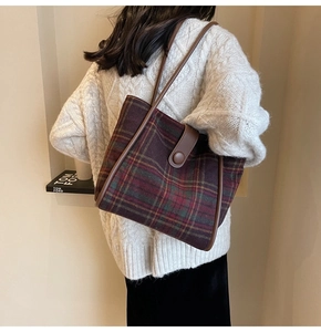 Detail of red and green plaid wool tote bag with brown leather straps for autumn fashion