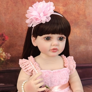 Close-up of a 55cm realistic reborn baby doll with brown hair and pink flower headband