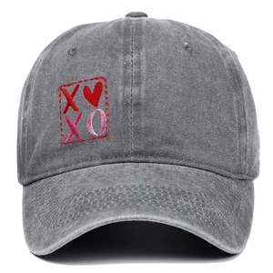 Dettaglio del ricamo XOXO rosso e motivo a cuore su berretto di jeans grigio