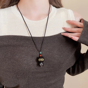 Detail of cute black cat wooden pendant with colorful beads on braided rope necklace