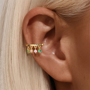 Close-up of a gold double-layer ear cuff with colorful star-shaped gemstone pendants