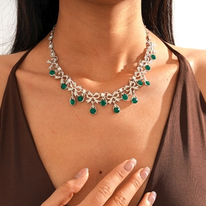 Close-up of vintage style silver necklace with green teardrop gemstones and bow design