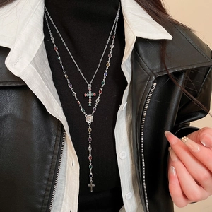 Detail of layered silver necklaces with colorful rhinestones and cross pendants on model