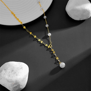Detailed view of golden Y-shaped sweater chain with white pearls on a grey background