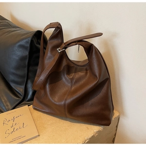 Detail of brown soft PU leather tote bag with metallic buckle on a textured surface