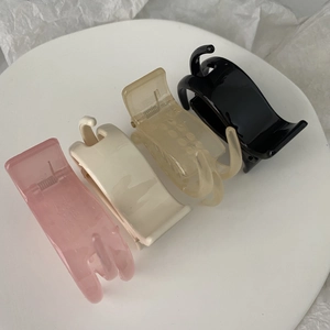 Group of 5cm three-tooth hair clips in pink, beige, yellow, and black on a white tray