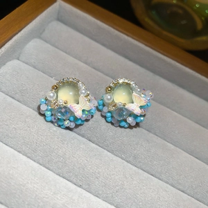 Detail showing resin butterfly earrings with blue beads and crystals on a velvet display