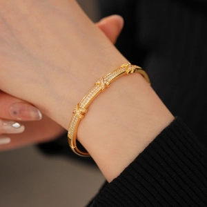 Detailed close-up of 18k gold plated X-shaped bangle featuring micro-pave cubic zirconia