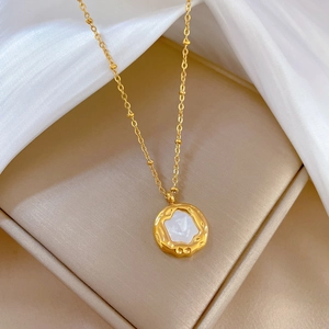 Gold titanium steel necklace with irregular shell pendant on white silk background