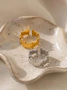 Detail of gold and silver irregular textured open rings on a ceramic jewelry tray