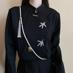 Detail of multi-layer body chain with lotus pendant, faux pearls and tassels on black top