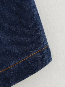 Gros plan détaillé du tissu denim bleu avec surpiqûres orange et texture de matière