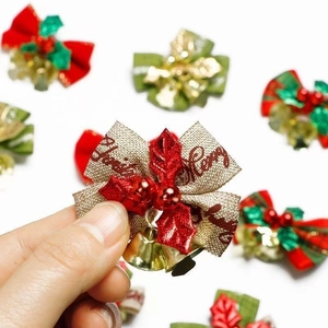 Hand holding Christmas bow ornament with gold bell, red berries and Merry Christ text