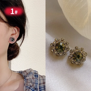 Close-up of vintage flower earrings with green gemstone and champagne crystal halo
