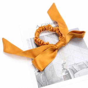 Ginger yellow 100% mulberry silk scrunchie with elegant long ribbons on a magazine