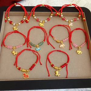 Vue détaillée de bracelets tressés rouges avec pendentifs cheval dorés et perles cristal