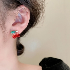 Close-up of red cherry studs with green crystal leaves and sparkling diamond detail