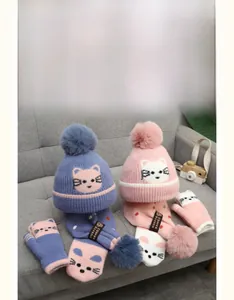 Detailed view of kids' winter knitted set featuring cartoon cat patterns and fur pom-poms