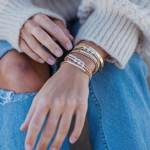 Detailed view of layered baroque pearl bracelets with a gold screw pattern bangle
