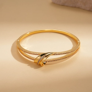 Detail of 18k gold plated double-layer bangle with twisted knot and pavé cubic zirconia