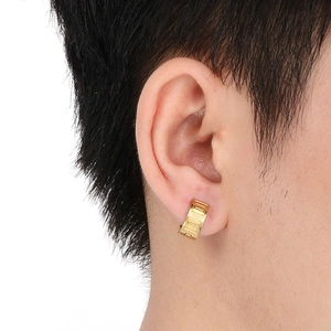 Close-up of gold hoop earrings with Roman numerals engraving on a female model's ear