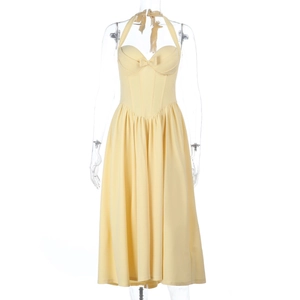 Detail of yellow halter neck dress featuring a waist-cinching bow and pleated A-line hem