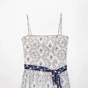 Robe blanche élégante à bretelles avec imprimé floral bleu et ceinture assortie